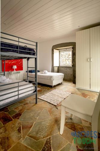 a bedroom with two bunk beds and a bench at Casa dos Calços in Angra do Heroísmo