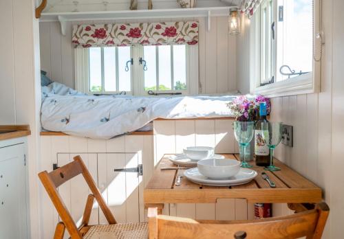 a small kitchen with a table and a bed at The Shepherds Hut at Anvil House in Woodbridge