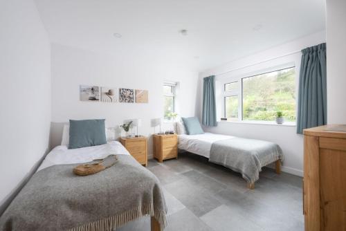 een slaapkamer met twee bedden en een raam bij 10 The Valley - Free Parking & WiFi, Close To Beaches in Porthcurno