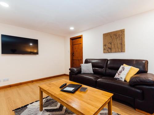 The Barn في Girthon: غرفة معيشة مع أريكة جلدية وطاولة قهوة