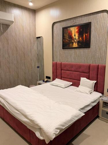 a bedroom with a large bed with a red headboard at Homyana stays in Jāmb