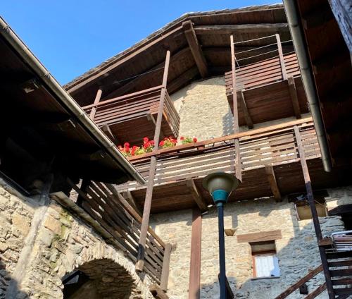 un edificio con balconi in legno con fiori di Maison di Viola a Arliod