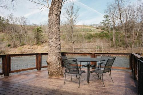 a table and chairs on a deck next to a tree at Laurel Bush Combo - 6 Waterfront Homes, Fish, Hike, and Mountain Views! in Sylva