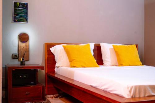 una camera da letto con un letto con cuscini gialli e una TV di Le Jardin Arhumatic Sambava a Sambava