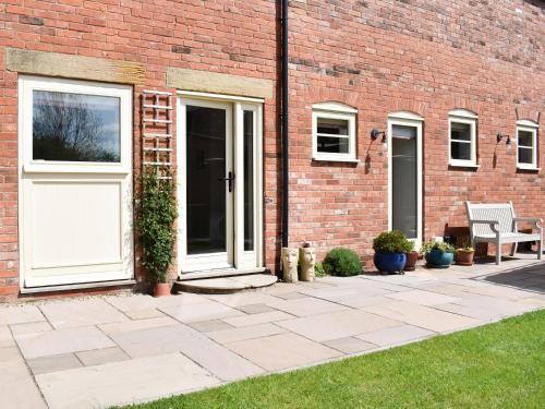 a brick building with a white door and a bench at White Heather Barn in Swanwick