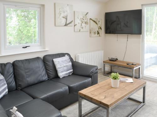 a living room with a black couch and a table at Little Fawn in Otterburn
