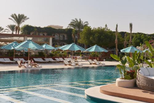 a swimming pool with lounge chairs and blue and white umbrellas at Desert Rose in Hurghada