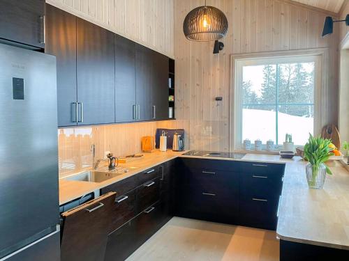 Una cocina con gabinetes negros y un fregadero y una ventana. en New Cabin With Mountain View In Bittermark, Trysil, en Trysil