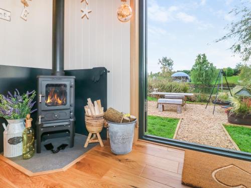 a fireplace in a living room with a view of a yard at Poppie's Shepherd Hut - Uk50227 in Redmile
