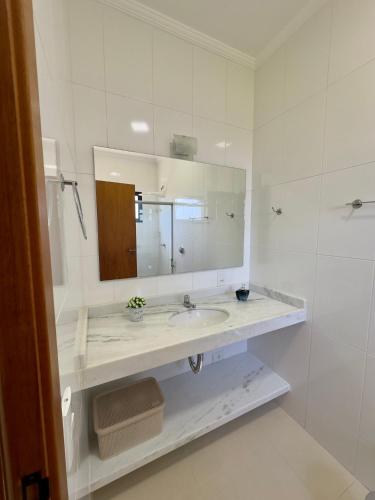 a white bathroom with a sink and a mirror at Vila dos Pinheiros 3 in Serra Negra
