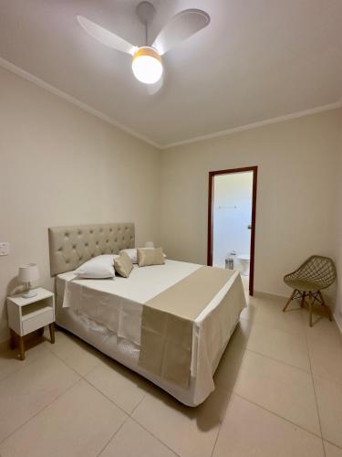 a white bedroom with a bed and a ceiling fan at Vila dos Pinheiros 3 in Serra Negra
