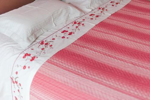 a pink and white bed with red flowers on it at B&B Casa Roman & Vakantiewoning voor 1 pers tot max 32 personen in Zonhoven