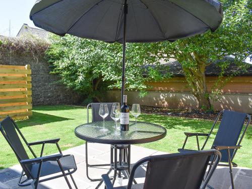 a table with wine glasses and an umbrella at Beckside House in Dalton in Furness