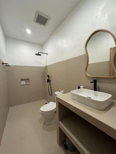 a bathroom with a sink and a toilet and a mirror at Aluna Villa Kintamani - Private villa & Hot spring pool in Kubupenlokan