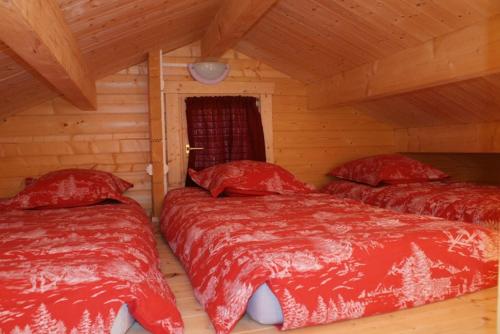 Twee bedden in een hut met rode lakens. bij Chalets Sybelles in Saint-Sorlin-dʼArves