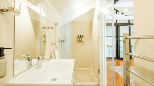 een witte badkamer met een wastafel en een douche bij Waymaker Cottage in Franschhoek