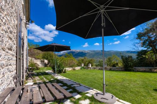 a patio with a bench and an umbrella at Apeiros Chora Hotel in Kato Pedina