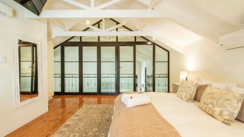 een woonkamer met een witte bank en grote ramen bij Waymaker Cottage in Franschhoek