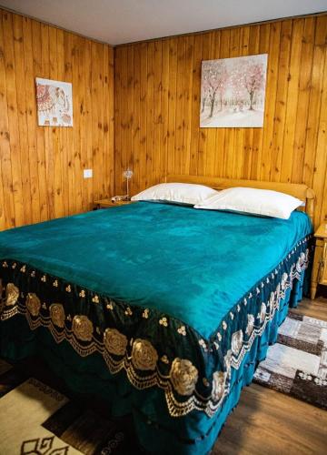 a bedroom with a large blue bed with wooden walls at FLH - Trofeul Cerbului in Negrileşti