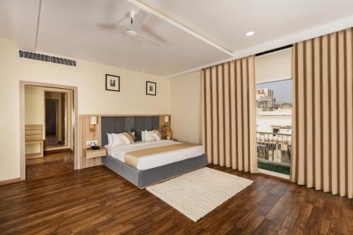 a bedroom with a bed and a large window at asar Capoors Hotel Hazratganj by Orion Hotels in Lucknow