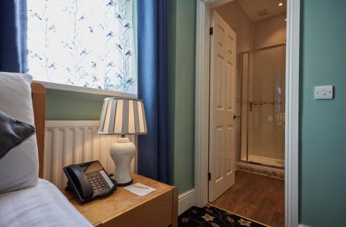 a bedroom with a bed and a telephone on a table at Stone House Hotel ‘A Bespoke Hotel’ in Stone