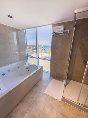 a large bathroom with a tub and a shower and acean at Ilica Hotel Spa & Wellness Resort in Çeşme