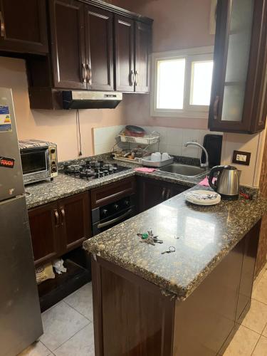 a kitchen with wooden cabinets and a granite counter top at Cozy Mini Villa with a backyard in 6th Of October