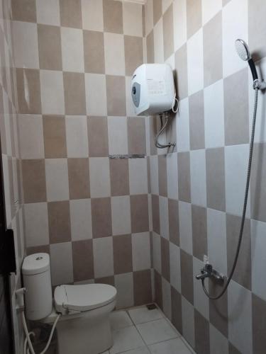 a small bathroom with a toilet and a shower at Villa Kusuma Pinus M10 in Batu