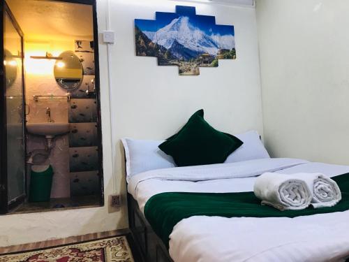 two beds in a room with a mountain picture on the wall at Mita Hotel in Dhulikhel