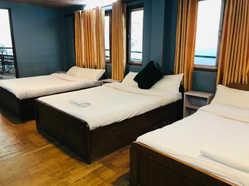 three beds in a room with windows at Mita Hotel in Dhulikhel