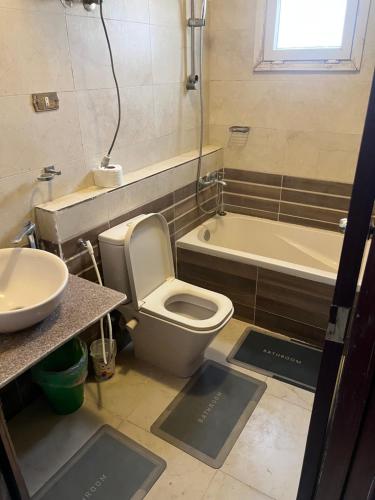 a bathroom with a toilet and a sink and a tub at Cozy Mini Villa with a backyard in 6th Of October