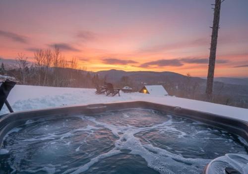 a hot tub in the snow with a sunset in the background at Modern Comfort - Spa - Mountain - Chalet KNOX in Saint Come