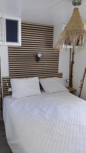 een slaapkamer met een wit bed met een houten hoofdeinde bij Julieregis in Biscarrosse