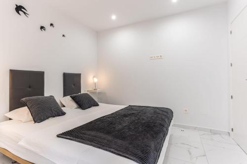 ein weißes Schlafzimmer mit einem großen Bett und schwarzen Kissen in der Unterkunft Casa Arne in Torrevieja