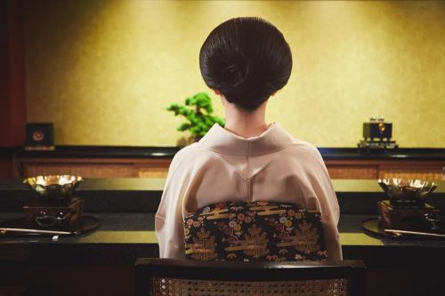 a woman sitting in a chair at a table at ご当地ラーメン食べ放題 "The RAMEN HOTEL" -京都嵐山- in Kyoto
