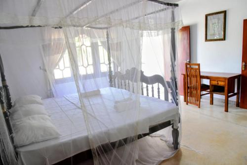 un dormitorio con una cama con dosel en Accoma Villa, en Hikkaduwa