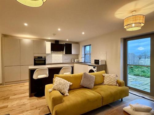 a living room with a yellow couch and a kitchen at Woodland View House in Norton Canon