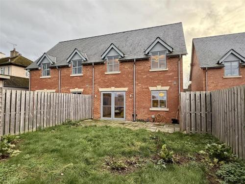 a brick house with a fence in front of it at Woodland View House in Norton Canon