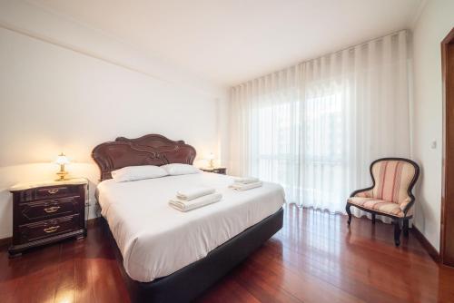 una camera da letto con un letto grande e una sedia di Esmael Apartment By Mth a Funchal