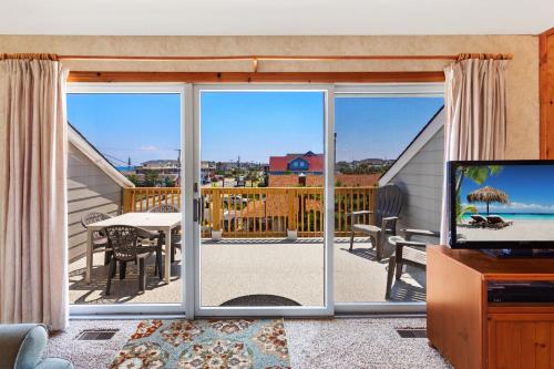 a living room with a view of a balcony with a television at AC1H - Seawind in Nags Head
