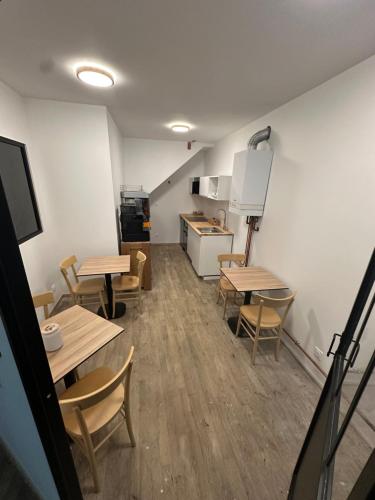 a room with tables and chairs and a kitchen at Suite 3- La Petite Auberge in Langres