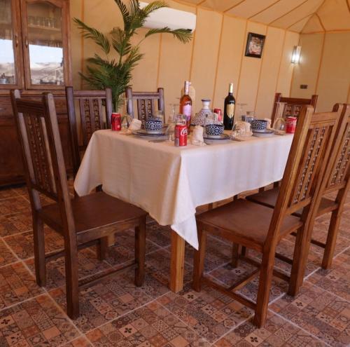 a dining room table with a white table cloth and chairs at Desert Pearl Camp in Merzouga