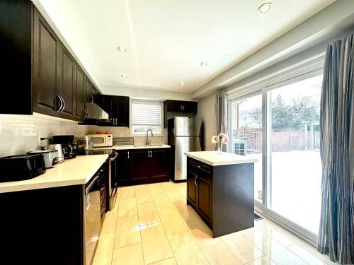uma cozinha com armários pretos e uma grande janela em Cozy Queen room with Shared Bath near Seneca Finch 404 em Toronto