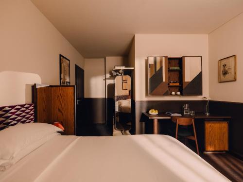 Un dormitorio con una cama, una mesa y un espejo. en Aethos Milan, en Milán