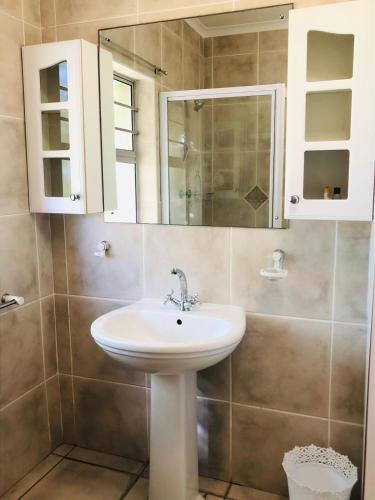 a bathroom with a sink and a mirror at PJ Guest House in Gqeberha