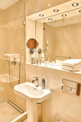 a white bathroom with a sink and a shower at Strandhotel Strande in Strande