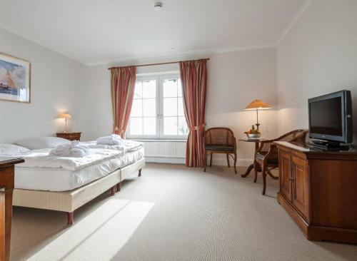 um quarto com uma cama, uma televisão e uma escrivaninha em Strandhotel Strande em Strande