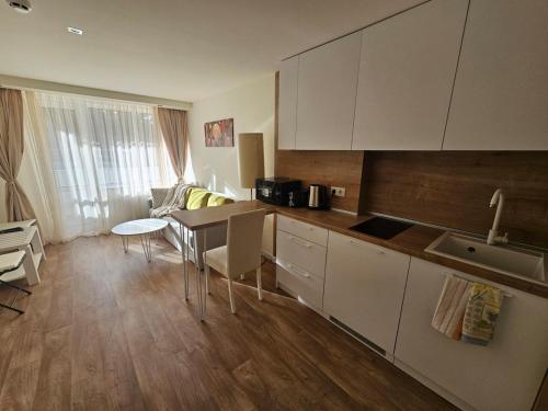 una cucina con mobili bianchi e un tavolo con sedie di Sunlit Forest Suite a Borovets