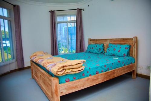 ザンジバルシティにあるMbweni Apartmentの窓のある部屋に青い枕が置かれた木製のベッド