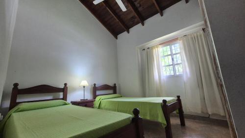 2 letti verdi in una camera con finestra di Ayres de Colon a Colón